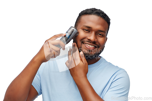 Image of smiling african man shaving beard with trimmer