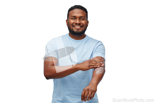 Image of happy african man applying moisturizer to his hand