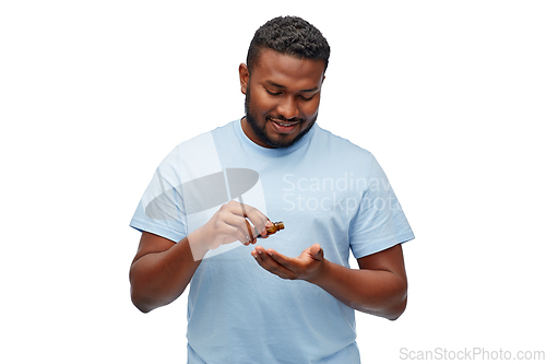 Image of african man applying grooming oil to beard