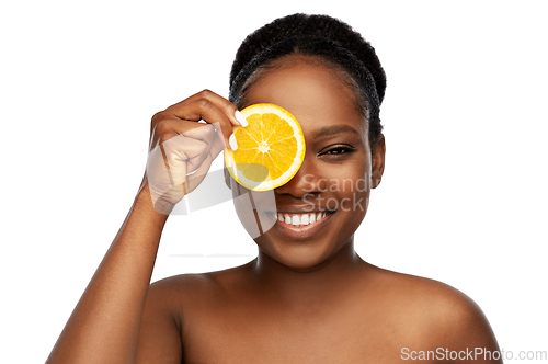 Image of smiling african woman making eye mask of oranges