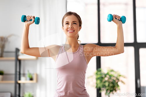Image of smiling young with dumbbells exercising at home