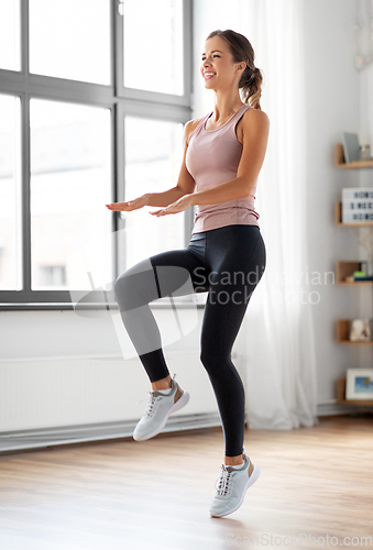 Image of smiling young woman exercising at home