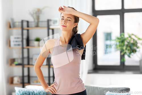 Image of tired young woman with towel after fitness at home