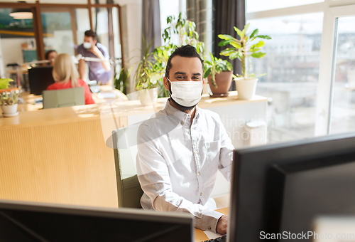 Image of creative male office worker in mask with computer