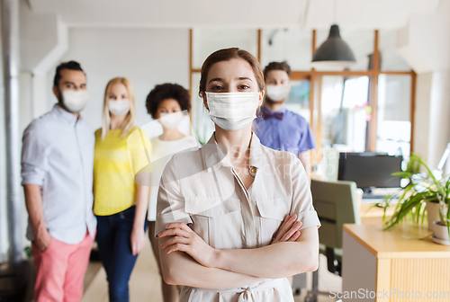 Image of woman in mask over creative team at office