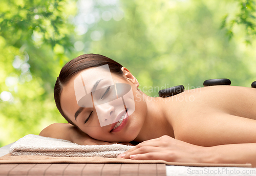 Image of smiling woman having hot stone massage at spa