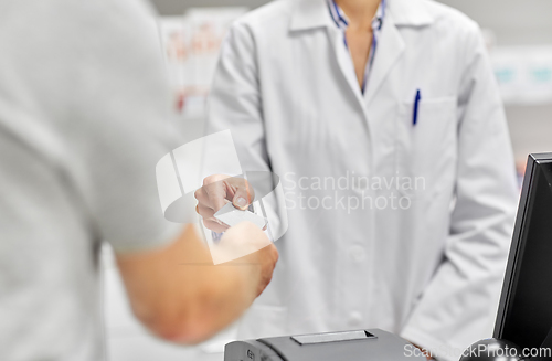 Image of close up of hand giving bank card to pharmacist