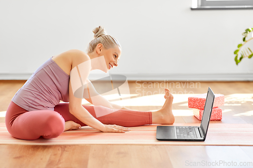 Image of woman with laptop exercising at yoga studio