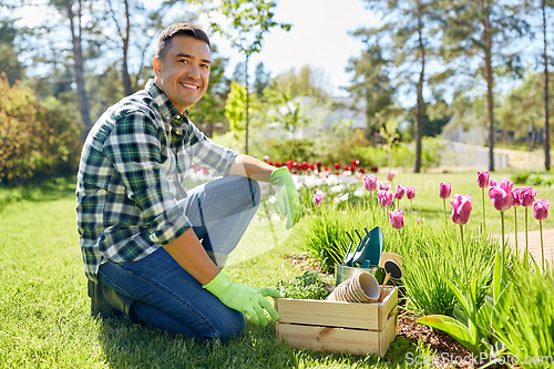 Image of happy man with tools in box and flowers at garden