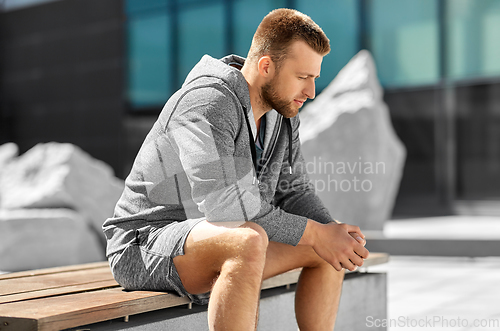 Image of young man sitting on bench outdoors