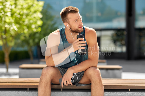 Image of sportsman with earphones and bottle in city