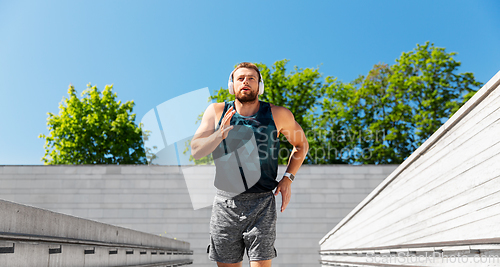 Image of young man in headphones running outdoors