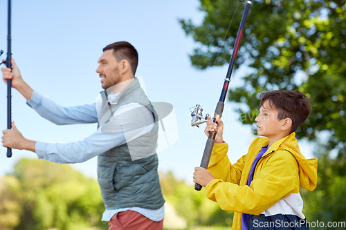 Image of happy smiling father and son fishing on river