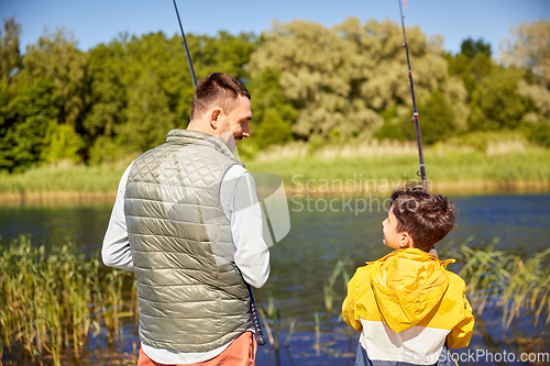 Image of happy smiling father and son fishing on river