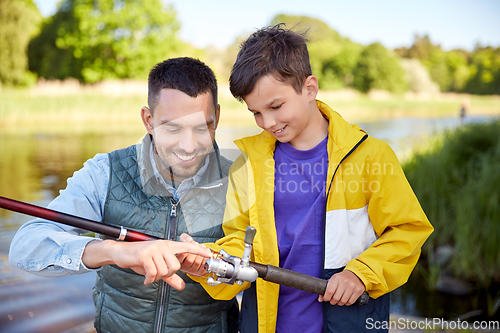 Image of happy smiling father and son fishing on river