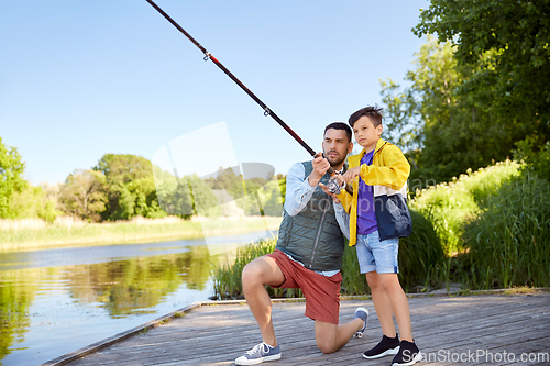 Image of happy smiling father and son fishing on river