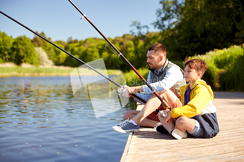 Image of happy smiling father and son fishing on river