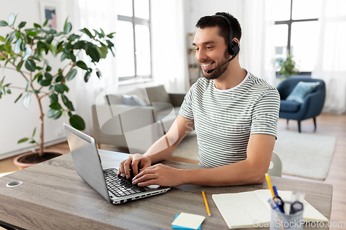 Image of man with headset and laptop working at home