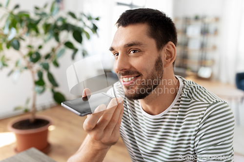 Image of man calling or recording voice with phone at home