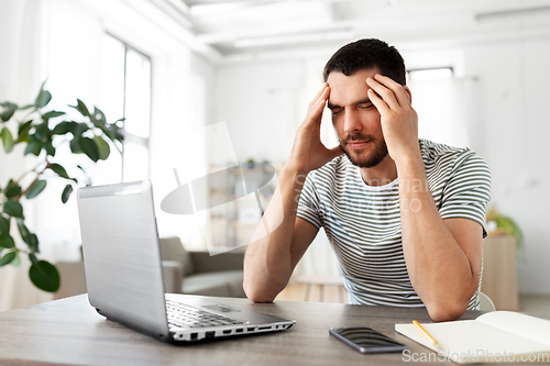 Image of stressed man with laptop working at home office