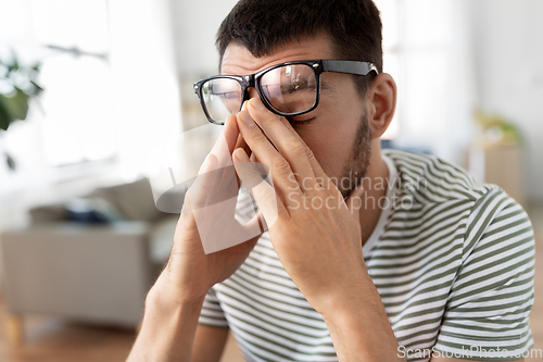 Image of tired man with glasses at home office