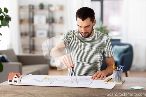 Image of architect with blueprint working at home office