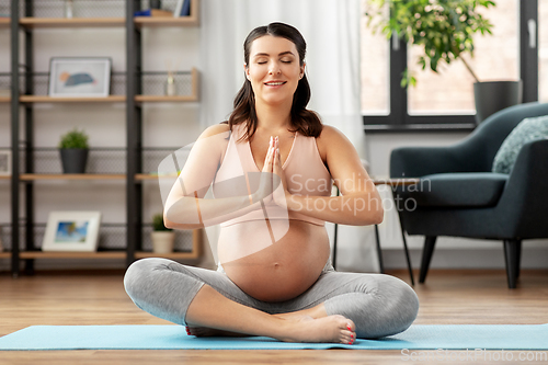 Image of happy pregnant woman meditating at home