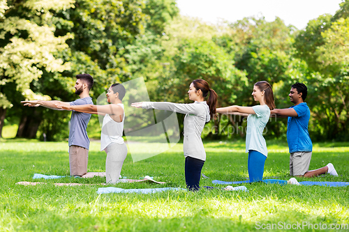 Image of group of people doing yoga at summer park