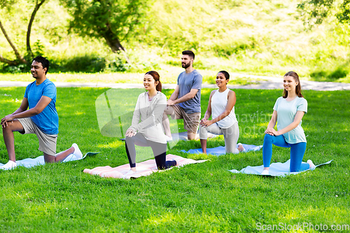 Image of group of people doing yoga at summer park