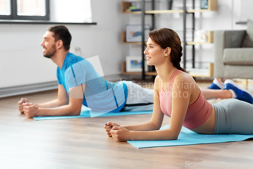 Image of happy couple exercising at home