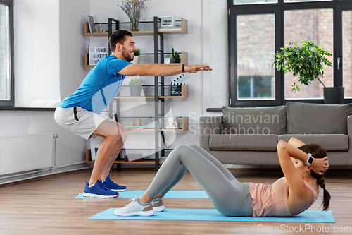 Image of happy young man and woman exercising at home