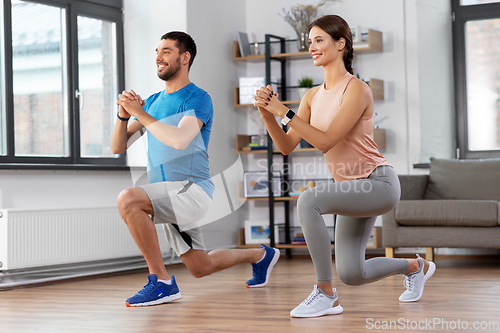 Image of happy couple exercising and doing squats at home