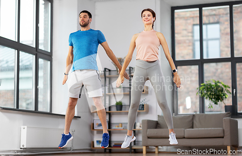 Image of happy couple exercising at home