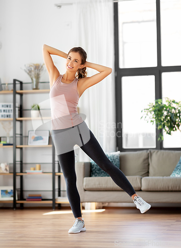 Image of smiling young woman exercising at home