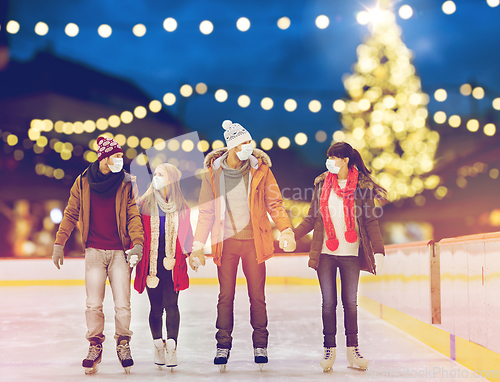 Image of friends in masks on christmas skating rink