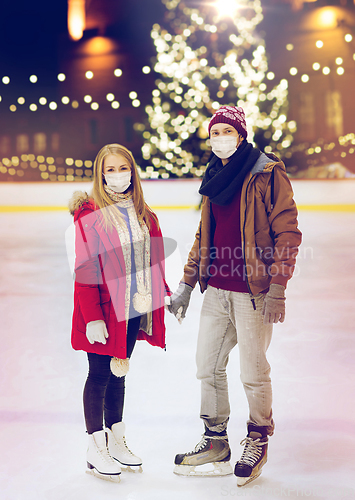 Image of couple in masks holding hands on skating rink