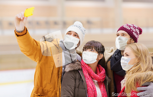 Image of friends in masks taking selfie on skating rink