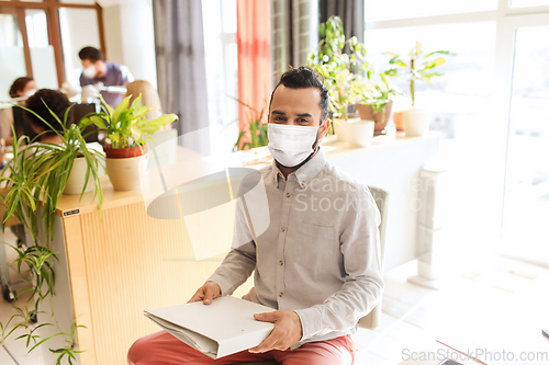 Image of creative male office worker in mask with folder