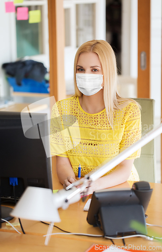 Image of businesswoman in mask with computer at office