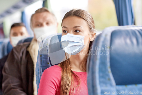 Image of young woman in mask sitting in travel bus or train