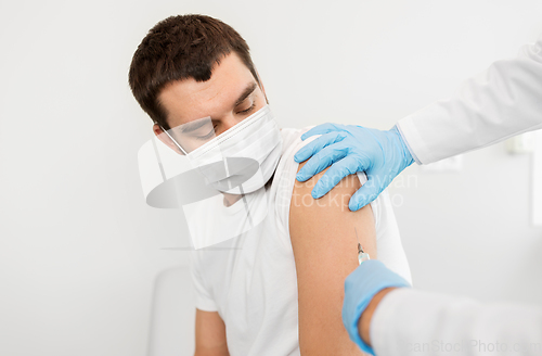 Image of male patient in mask and doctor hands with syringe