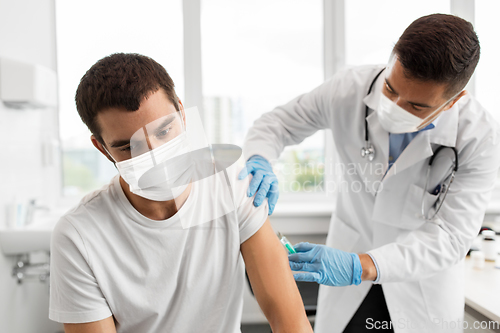 Image of patient and doctor in masks doing vaccination