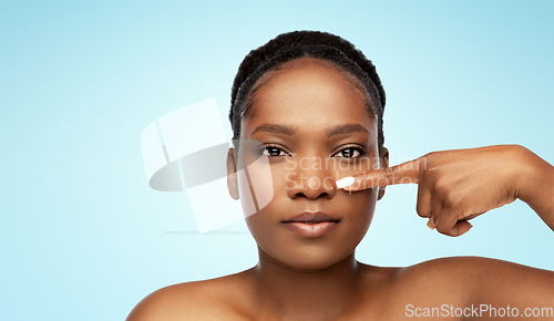 Image of portrait of african woman pointing to her nose