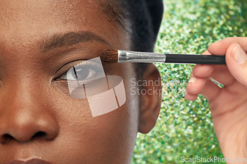 Image of face of african woman and hand with make up brush