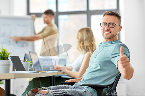 Image of happy man in glasses showing thumbs up at office