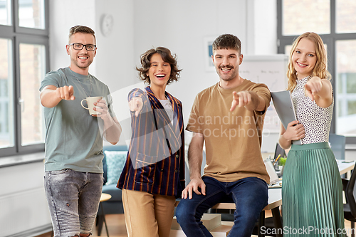 Image of business team pointing fingers to camera at office