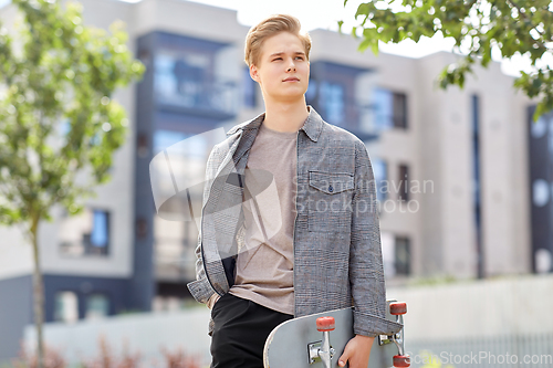 Image of teenage boy with skateboard on city street