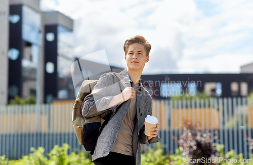 Image of young man with backpack drinking coffee in city