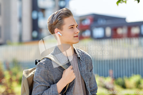 Image of young man with earphones and backpack in city