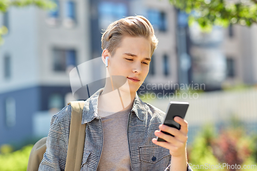 Image of teenage boy with earphones and smartphone in city